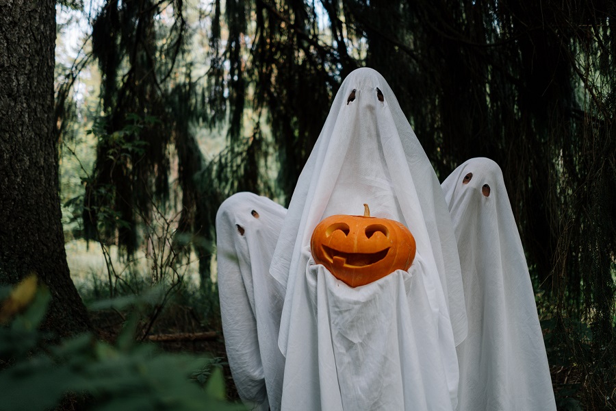 DIY Halloween Costumes  Three People Standing Outside Holding a Jack-O-Lantern While Wearing White Sheets with Eye Holes 