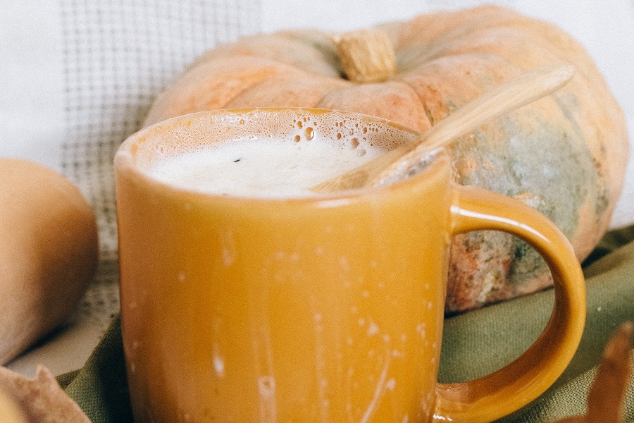 Pumpkin Drinks Close Up of an Orange Coffee Mug Filled with a Drink Sitting in Front of a Pumpkin