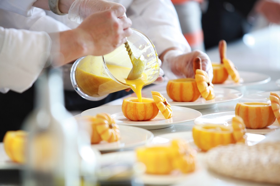 Pumpkin Drinks Close Up of a Waiter Pouring an Orange Drink Into a Small Pumpkin on a White Plate