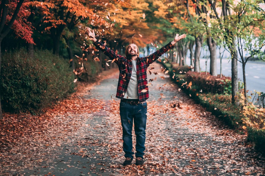 Stylish DIY Fall Décor a Man Standing on a Path Throwing Fall Leaves into the Air