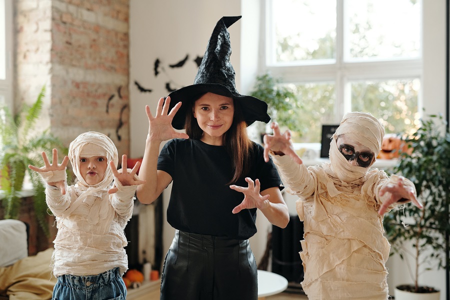You've Been BOOed Three Children, Two in Mummy Costumes and One in a Witch Costume Making a Boo Gesture with Their Hands