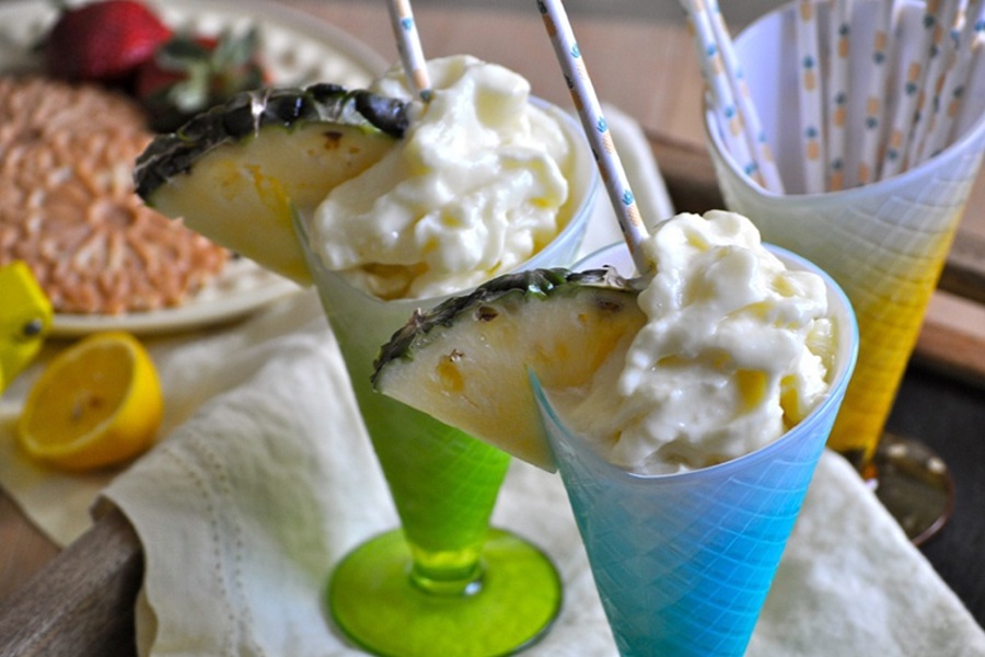 Make at Home Dole Whip Recipe A Blue GLass and a Green Glass Fileld with Dole Whip and Garnished with a Pineapple Wedge and a Straw