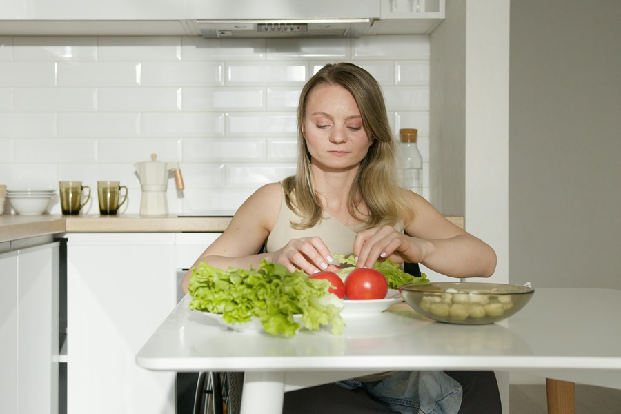 Master Your Metabolism Reviews and What's to Love a Woman Sitting at a Table in a Kitchen Eating Salad