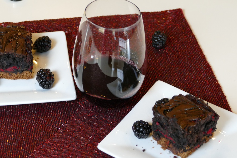 Better than Sex Brownies Recipe a Glass of Red Wine In Between Two Brownies Each on a Different White Plate with Blackberries