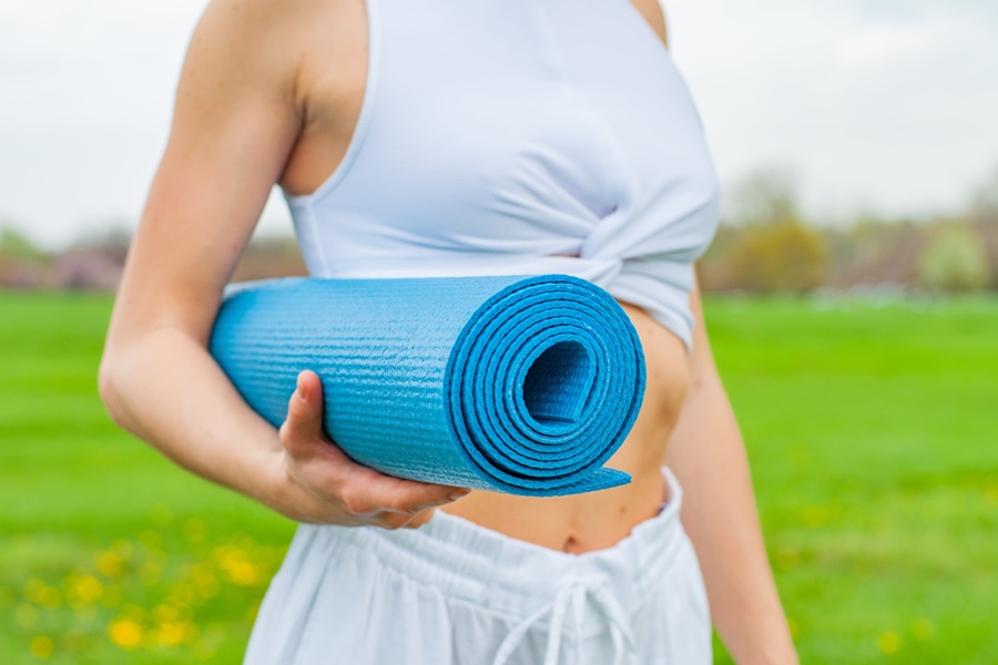 At Home Workout Equipment for Small Spaces Close Up of a Woman Carrying a Blue Yoga Mat