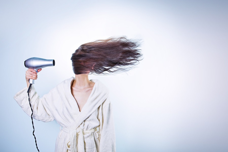 10 April Fools Jokes for Any Age a Woman Holding a Hair Dryer to Her head with Her Hair Blowing to One Side