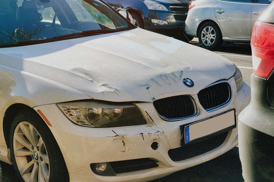 Awesome April Fool's Day Pranks to Play on your Husband Close Up of a White BMW Hood with Dents and Scratches All Over It