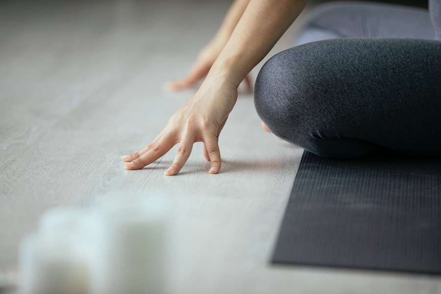 Morning Meltdown 100 Tips and Tricks Close Up of a Woman's Hands Touching The Floor In Front of Her While Sitting on a Yoga Mat