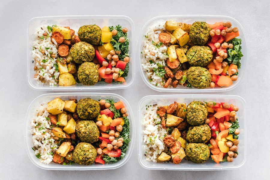 Whole30 vs Paleo vs Keto Overhead View of Four Meal Prep Containers Filled with Healthy Food