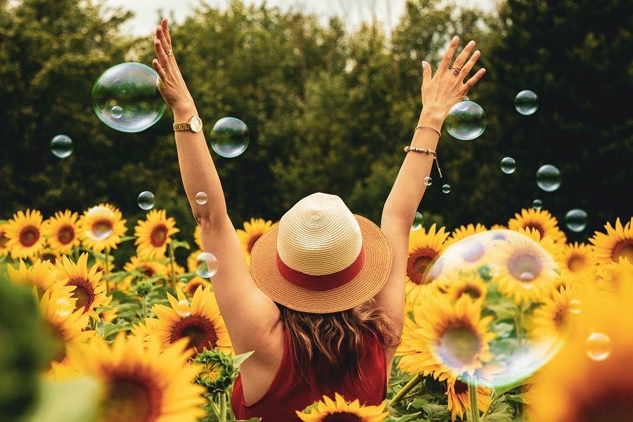 Colloidal Silver Uses a Woman Sitting in a Field of Sunflowers with Her Hands Up in Celebration
