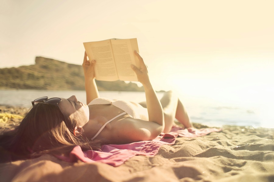 Beach Bag Essentials a Woman Lying on a Beach Reading a Book
