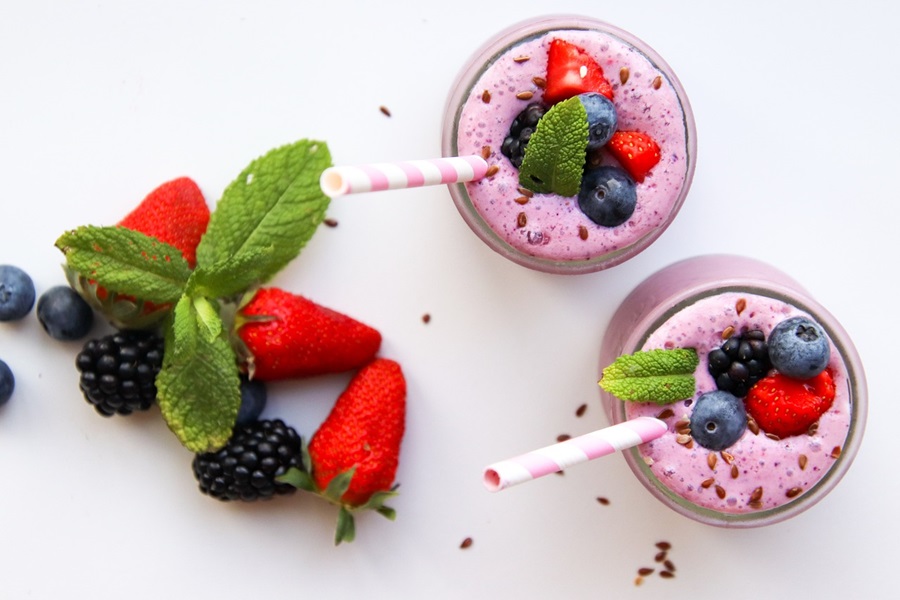 Smoothie Recipes to Reduce Bloating Overhead View of Two Glasses Filled with Pink Smoothies and Topped with Fresh Berries