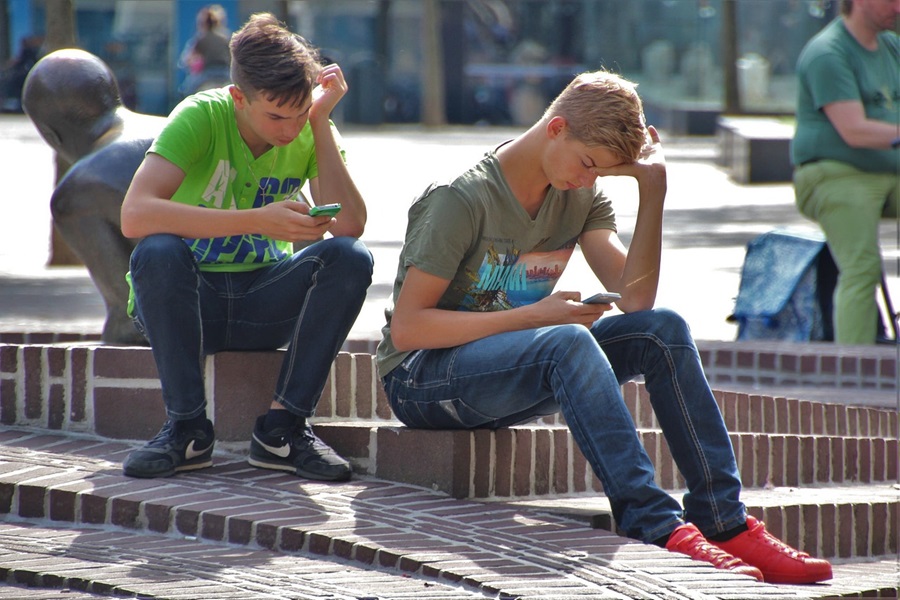Printable Cell Phone Contract for Tweens and Teens Close Up of Two Teen Boys Sitting Outside Playing On Their Phones