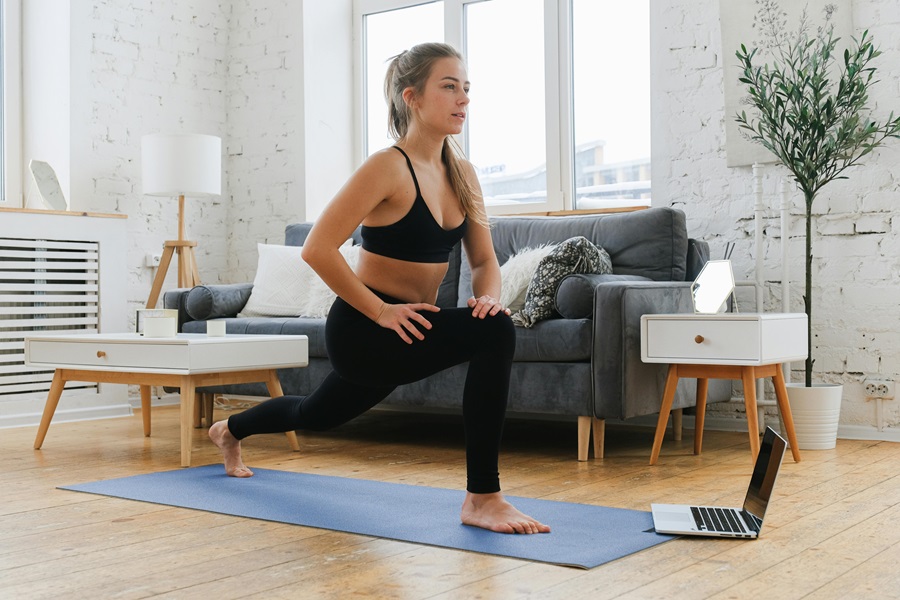 35 At Home Workouts for Women a Woman Doing Lunges in a Living Room with a Couch and Side Table Behind Her