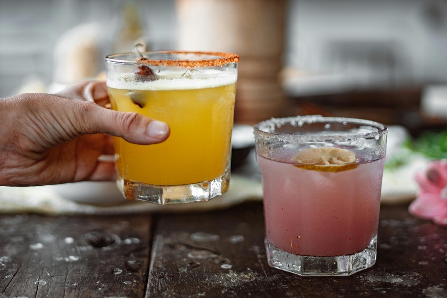 Best Winter Margarita Recipes for a Crowd A Hand Reaching for One of Two Margaritas on a Table