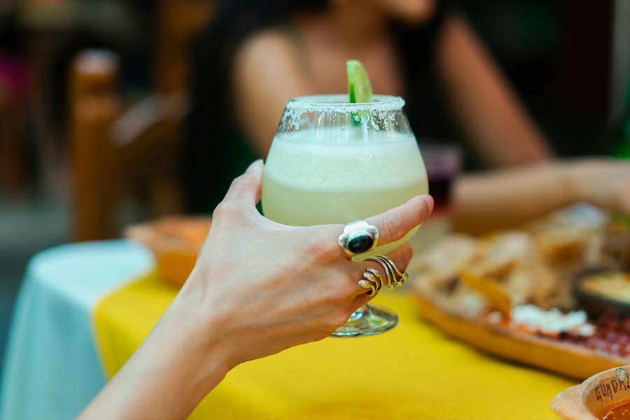 Best Winter Margarita Recipes for a Crowd Close Up of a Woman's Hand Holding a Margarita with a Salted Rim