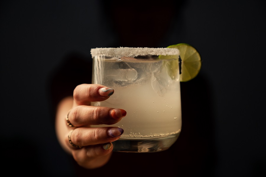 Best Winter Margarita Recipes for a Crowd a Person Holding Out a Margarita with a Lime Slice as Garnish