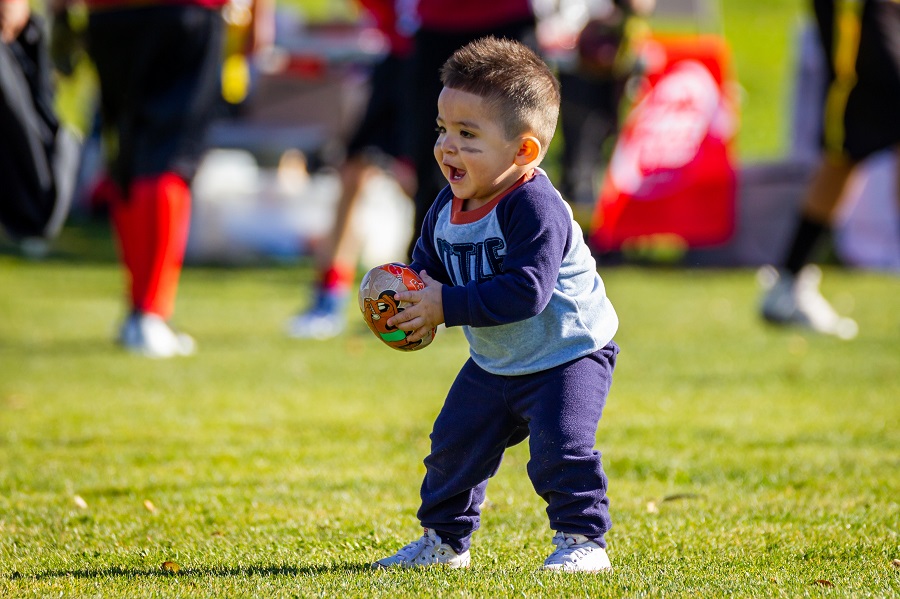 Super Bowl Party a Little Boy Holding a Football Standing on the Sidelines of a Game