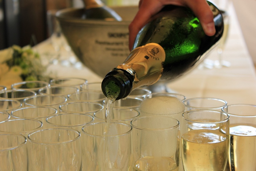 Best Champagne Cocktails for New Year's Eve Close Up of a Person Pouring Champagne into Glasses on a Table