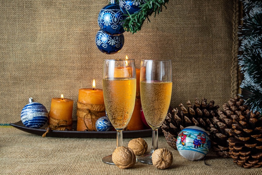 Best Champagne Cocktails for New Year's Eve Two Glasses of Champagne on a Floor with Christmas Tree Branches Hanging Over Them