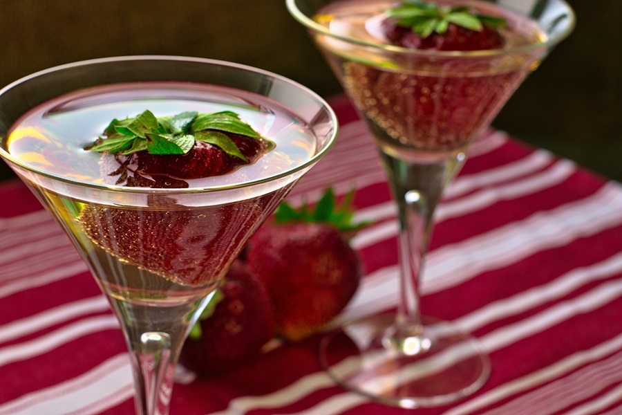 Best Champagne Cocktails for New Year's Eve Close Up of Two Champagne Glasses with Strawberries