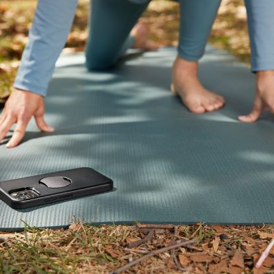 Otterbox Symmetry vs OtterGrip Symmetry Series for MagSafe Close Up of a Phone in a Case on a Yoga Mat with a Woman in a Yoga Pose