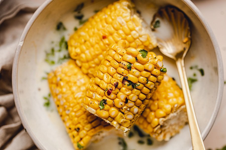 Slow Cooker Corn on the Cob with Coconut Milk Recipe Close Up of Corn on the Cob Halves in a Bowl with a Spoon