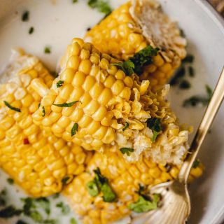 Slow Cooker Corn on the Cob with Coconut Milk Recipe Close Up of Corn on the Cob Halves in a Bowl Sprinkled with Cilantro