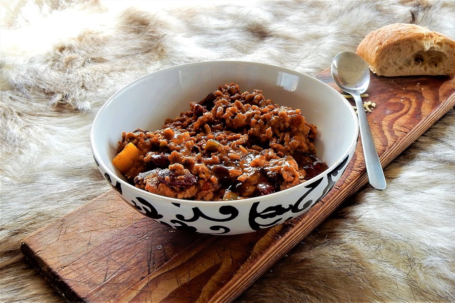 Keto Crockpot Chili Recipes Close Up of a Bowl of Chili on a Wooden Board with a Spoon