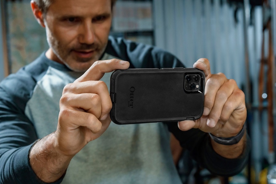 Otterbox Defender vs Commuter vs Symmetry a Man Holding Up a Phone in an Otterbox Case Taking a Picture of Something Out of View