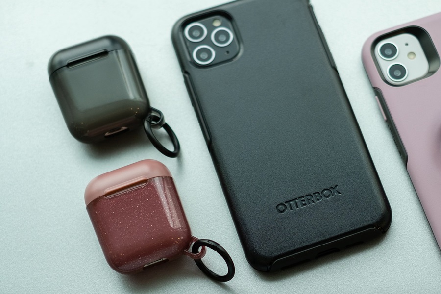 Otterbox Prefix vs Commuter a Phone in an Otterbox Case on a White Surface Next to Two Otterbox Airpod Cases