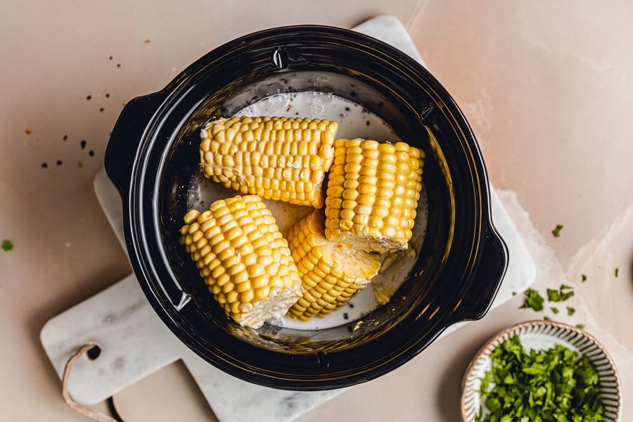 Slow Cooker Corn on the Cob with Coconut Milk Recipe Overhead View of a Crockpot with Corn Halves and Other Ingredients 
