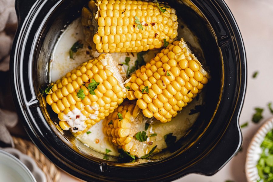Slow Cooker Corn on the Cob with Coconut Milk Recipe Close Up of a Crockpot with Corn Halves and Cilantro