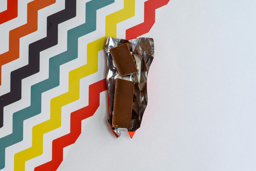 Low Carb Chocolate Dessert Recipes Overhead View of an Opened Chocolate Bar on a White Surface with Colorful Zig Zags