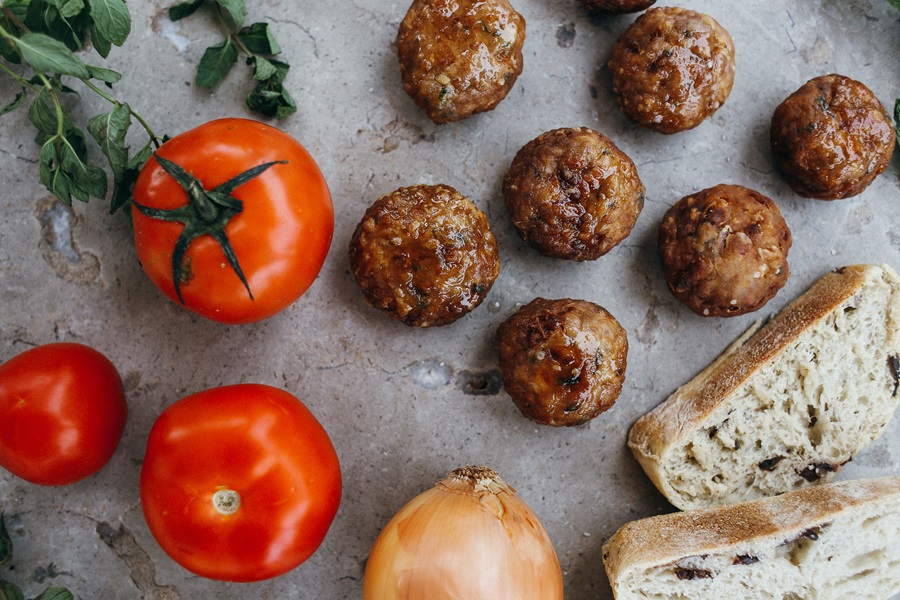 Low Carb Meatballs Recipe Ideas Meatballs on a Silver Surface Next to Tomatoes, Onions, and Sourdough Bread