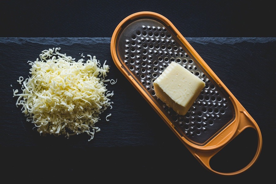 On the Go Keto Snacks Close Up of Cheese on a Cheese Grater Next to a Pile of Shredded Cheese