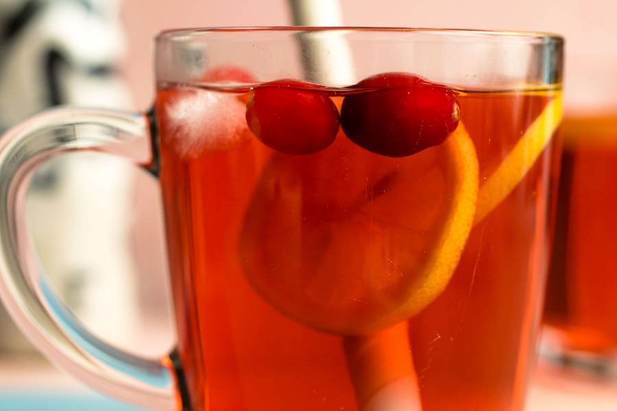 Jillian Michaels Detox Drink Recipe Close Up of a Glass Mug Filled with Detox Drink with a Slice of Orange and Two Cranberries