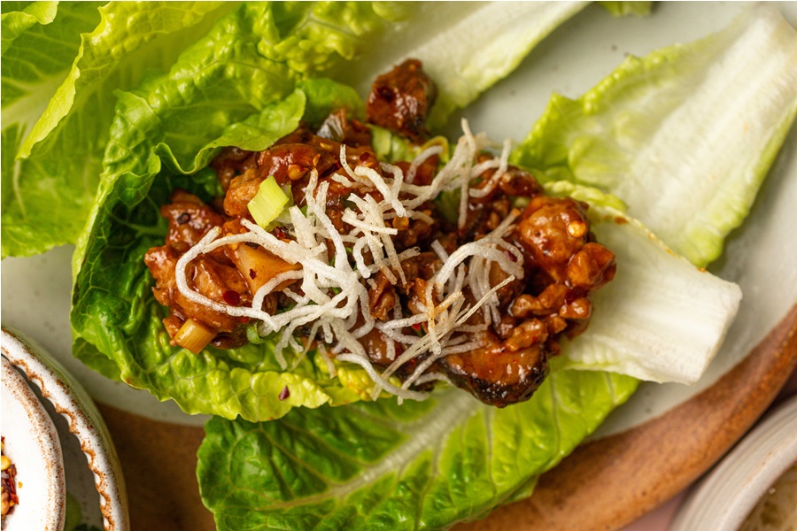 Copycat Pei Wei Chicken Lettuce Wraps Recipe Close Up of Chicken Lettuce Wrap Resting on Romaine Lettuce Leaves