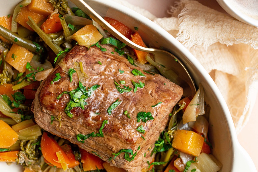 Old Fashioned Pot Roast Recipe in the Slow Cooker Close Up of a Pot Roast with Veggies in a Serving Dish with a Spoon