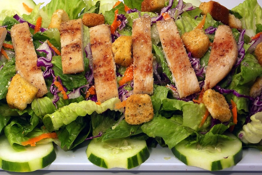Paleo vs Keto Close Up of a Salad Topped with Sliced Chicken