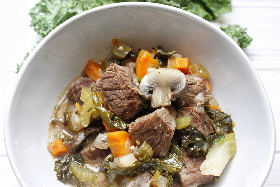Slow Cooker Low Carb Beef Stew Recipe a White Bowl of Low Carb Stew with Kale in the Background