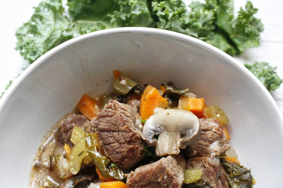 Quick and Easy Low Carb Beef Stew Recipe a White Bowl of Low Carb Stew with Kale in the Background