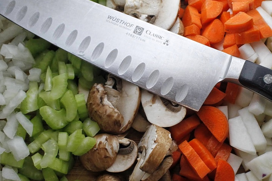 Slow Cooker Low Carb Beef Stew Recipe Close Up of a Knife Resting on Sliced Veggies Including Mushrooms, Carrots, and Celery