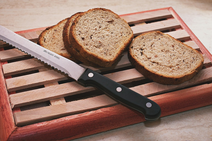 Is Gluten Free Bread Good for Diabetics Close Up of a Wooden Serving Tray with Wheat Bread Slices and a Bread Knife on Top