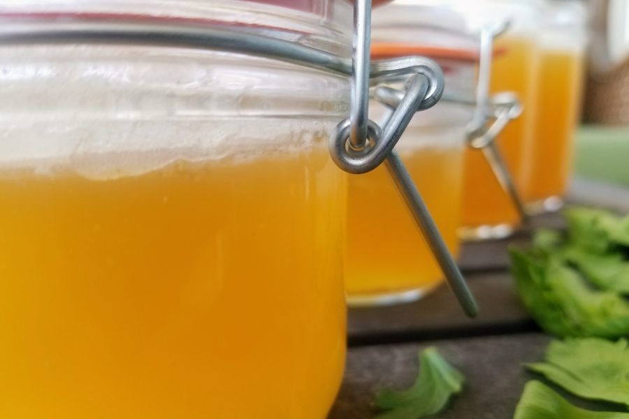 Healing Chicken Bone Broth Recipe Close Up of a Row of Glass Jars Filled with Broth