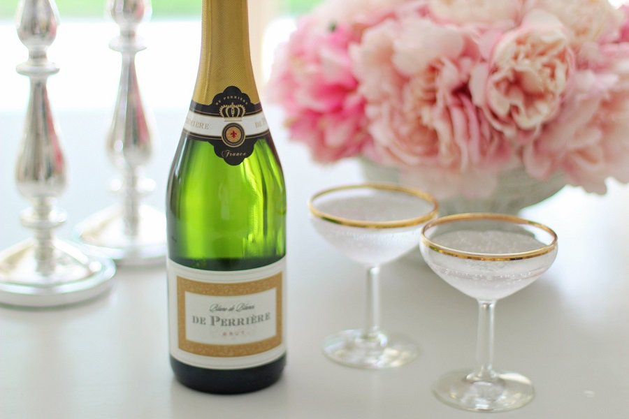 Easy Cocktails with Champagne a Bottle of Champagne on a Table with Two Champagne Glasses and a Centerpiece of Flowers