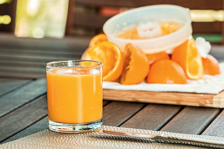 Fat Burning Juice Recipes  Close Up of a Glass of Orange Juice with Juiced Oranges in the Background