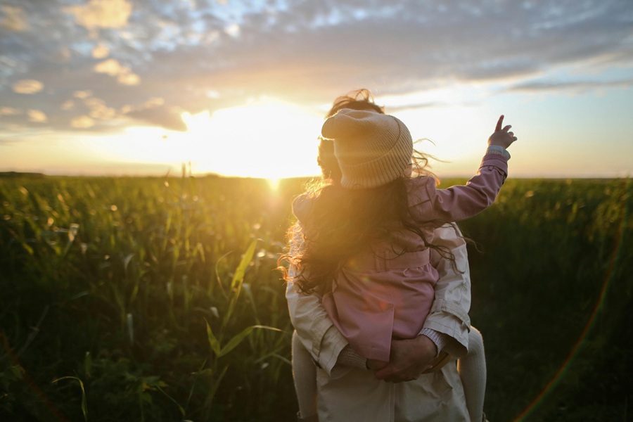 Healthy Mothers Day Breakfast Ideas a Mom Carrying Her Toddler Through a Field of Tall Grass with the Sun Setting in the Background