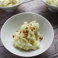 15 Minute Instant Pot Mashed Potatoes Close Up of Three Bowls Filled with Mashed Potatoes and Each Topped with a Different Garnish Including Bacon, Chives, and Cheese