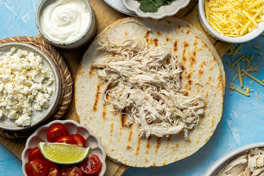 Easy Chicken Tacos with Shredded Chicken A Stack of Tortillas with Shredded Chicken on the Top of the First Tortilla